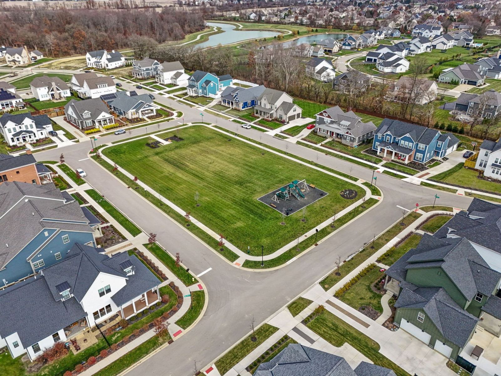 Aerial view of a neighborhood green with playground and pond in Evans Farm